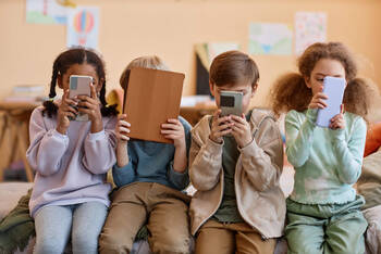Kinder sitzen vor Smartphones und Tablets