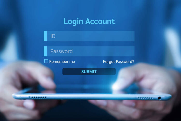 Eine Person hält ein Tablet in der Hand, auf dem ein Login-Feld zu sehen ist. 