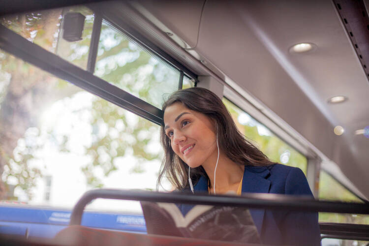 Frau sitzt im Bus und hört Musik