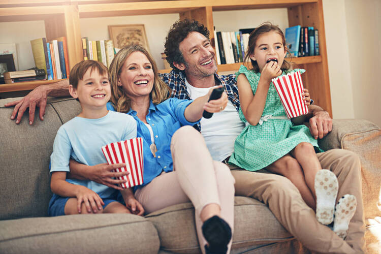 Eine Familie sitzt auf dem Sofa und schaut Fernsehen