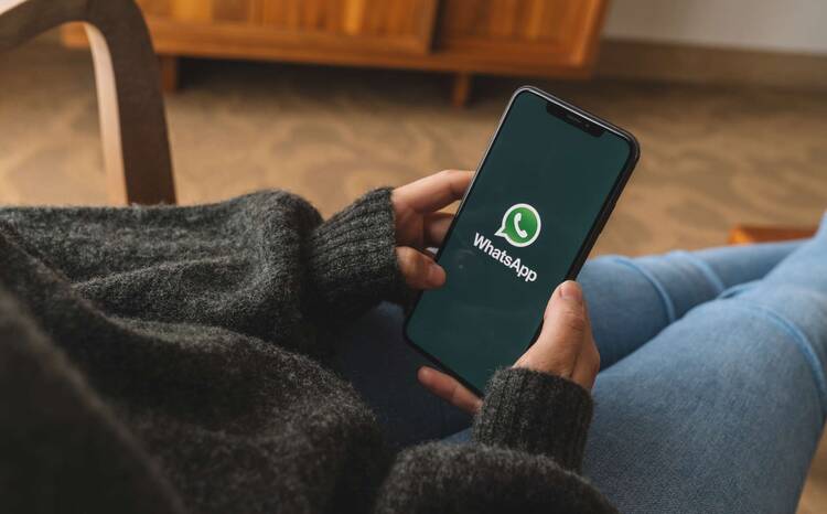 Frau hält Smartphone mit WhatsApp Splashscreen