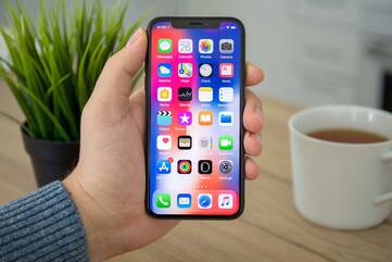 Hand hält iPhone der X-Reihe mit offenem Homescreen vor die Kamera