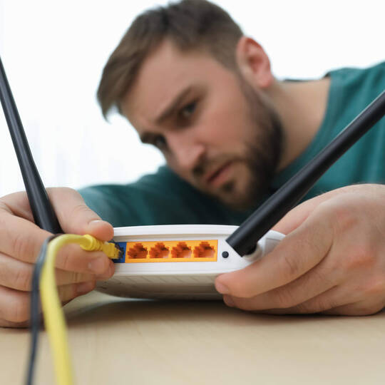 Ein Mann steckt die Kabel an einem Router um. 